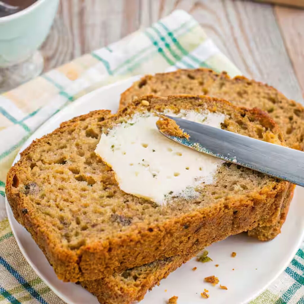 Gluten free zucchini bread slices with butter being spread