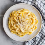 fettuccine carbonara on white plate with checkered towel