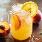 Homemade peach lemonade in a mason jar with lemon and peach slices