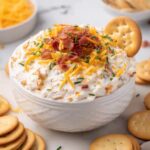 Cowboy crack dip topped with cheddar cheese, turkey bacon, and chives