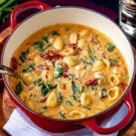 Marry Me Chicken Soup in a red pot with pasta, spinach, and sun-dried tomatoes
