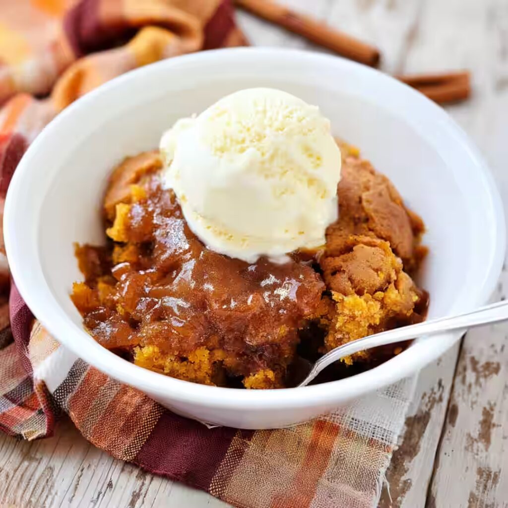 Pumpkin cobbler with vanilla ice cream in white bowl