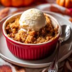 Pumpkin crisp served warm in red ramekin with vanilla ice cream