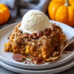 Warm pumpkin dump cake topped with vanilla ice cream and pecans