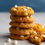 Pumpkin white chocolate chip cookies stacked on a light surface